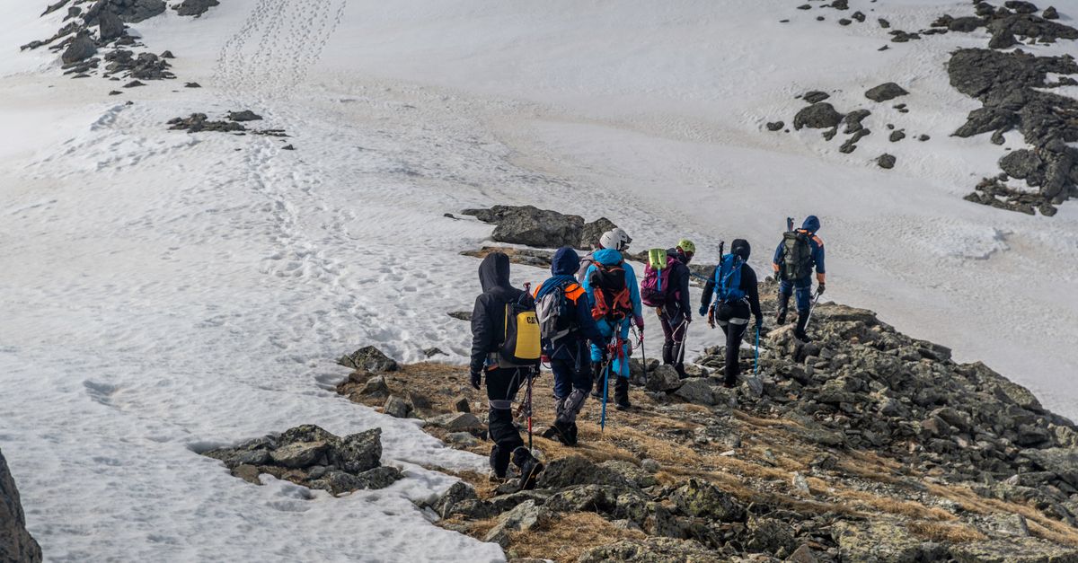 Adventurous group hiking on a snowy mountain ridge during winter, showcasing teamwork.